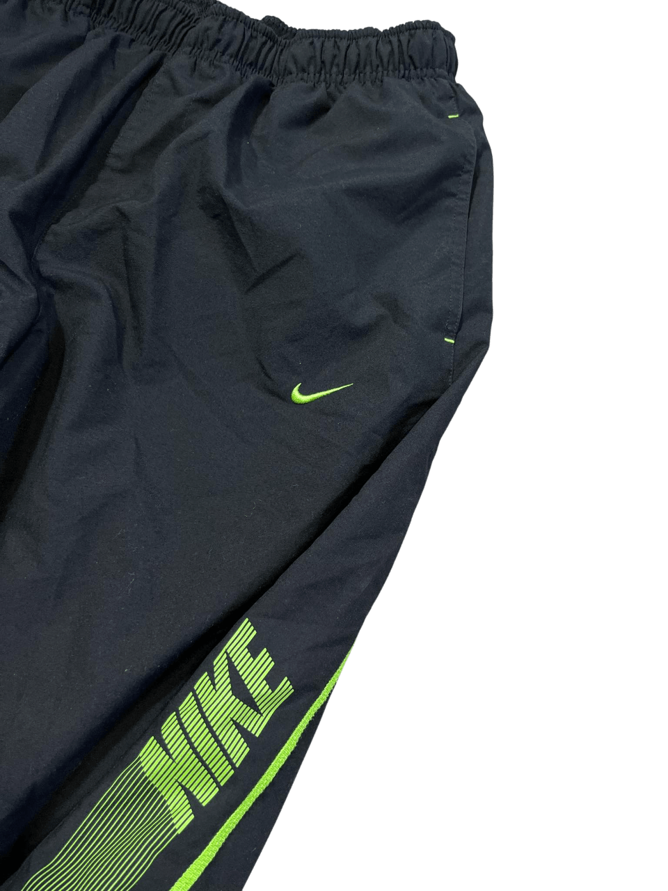Fekete Nike streetwear melegítőnadrág zöld logóval, vintage stílusban